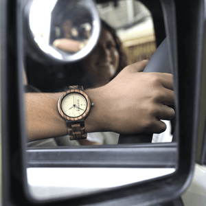 Reflection of man wearing a wooden watch while driving 