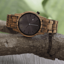 Load image into Gallery viewer, Zebrawood unisex wooden watch with black dial and blue second hand on a branch
