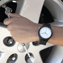 Load image into Gallery viewer, Person wearing ebony wooden watch while working on car
