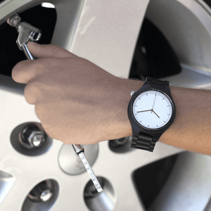 Person wearing ebony wooden watch while working on car