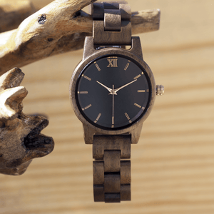 Walnut wooden watch with rose gold accents hanging off of branch