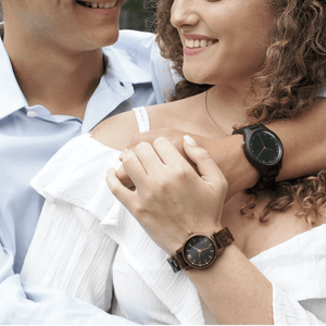 Two people modeling men's and women's wooden watches